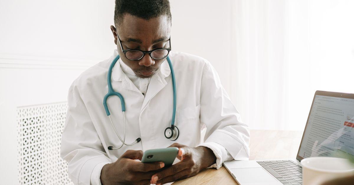 Profesional sanitario consultando información de trabajo en el móvil junto a un ordenador