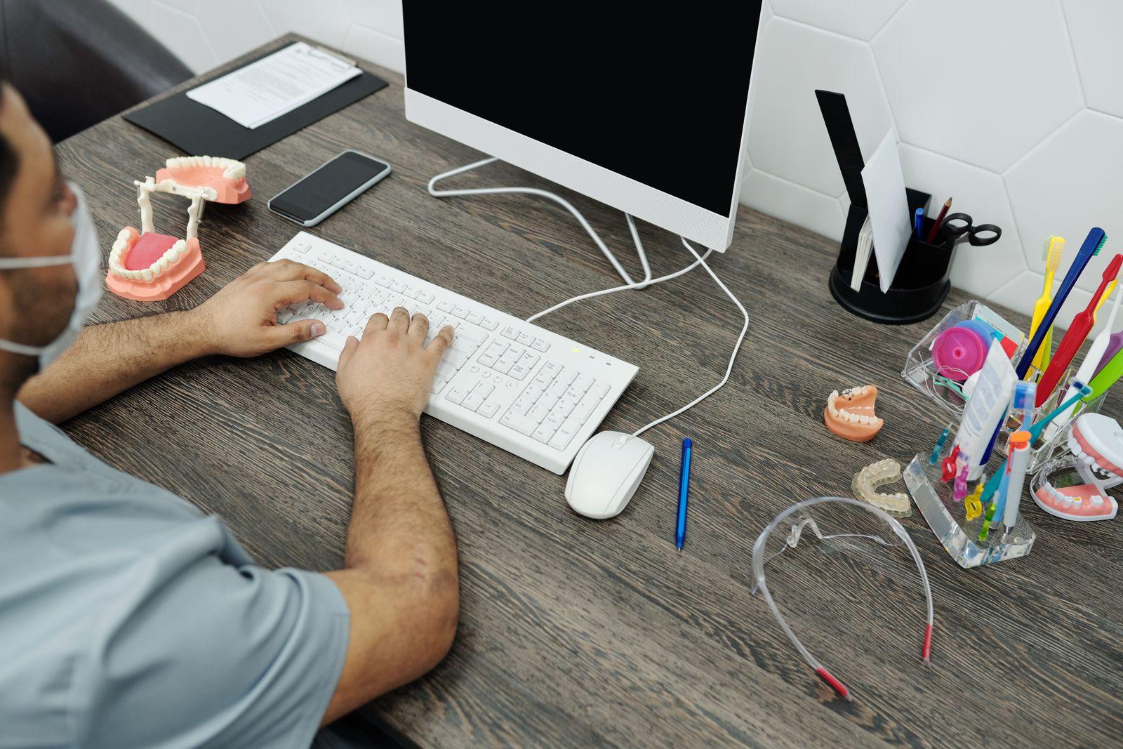 Profesional de una clínica dental consultando la ficha de un paciente en el ordenador