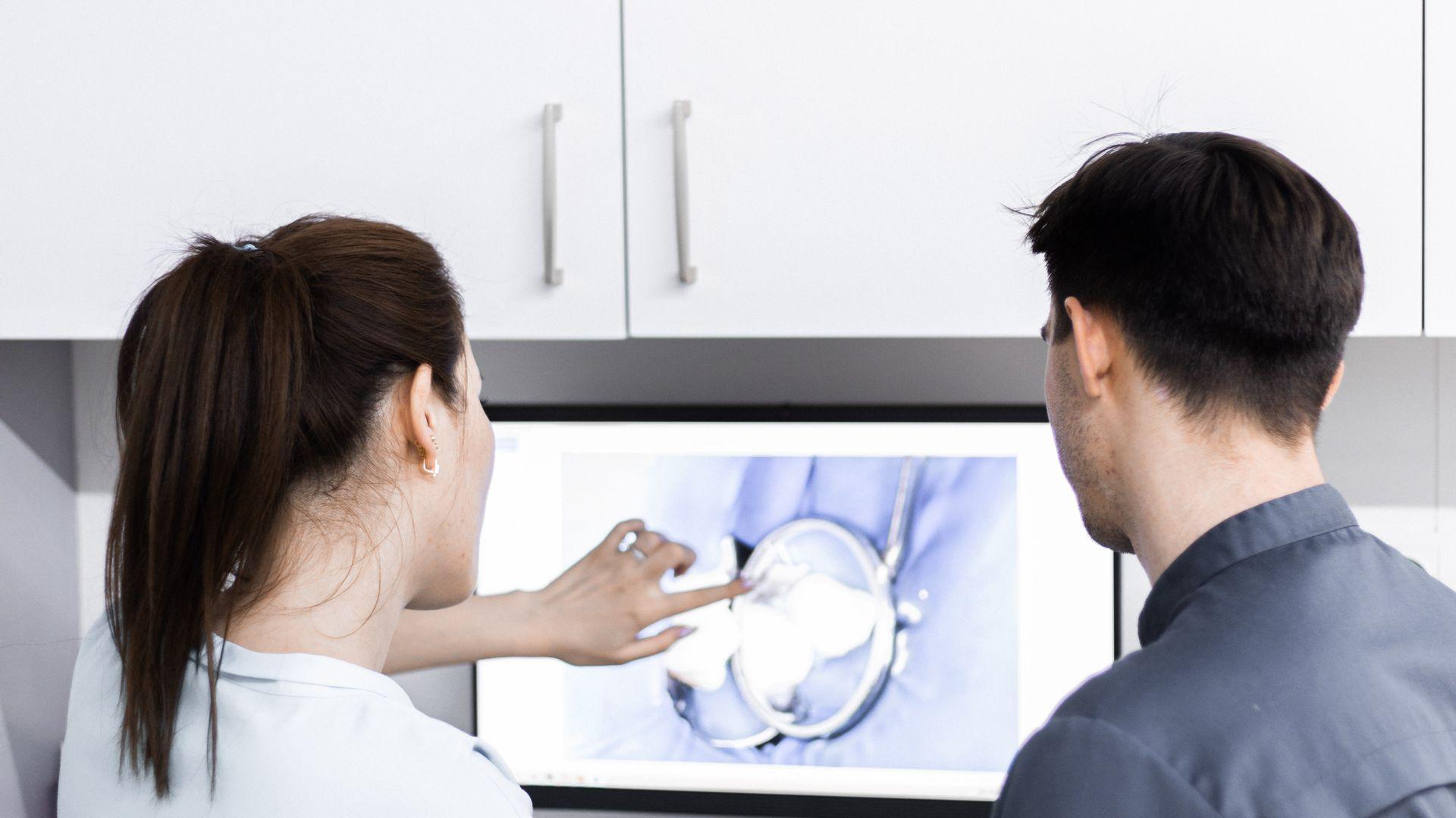 Dos profesionales de clínica revisando información dental en una pantalla antes de tomar una decisión
